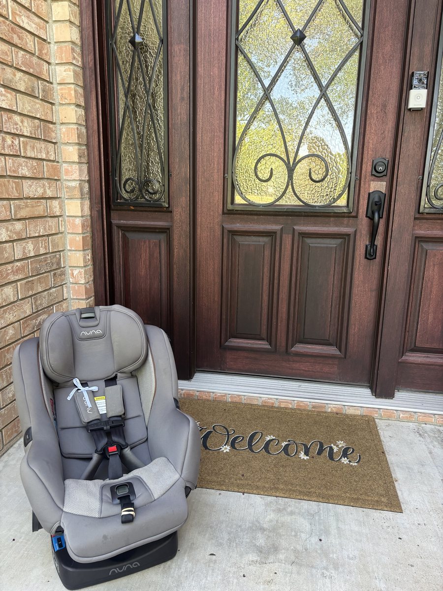 A Nuna car seat on a front porch next to the welcome mat